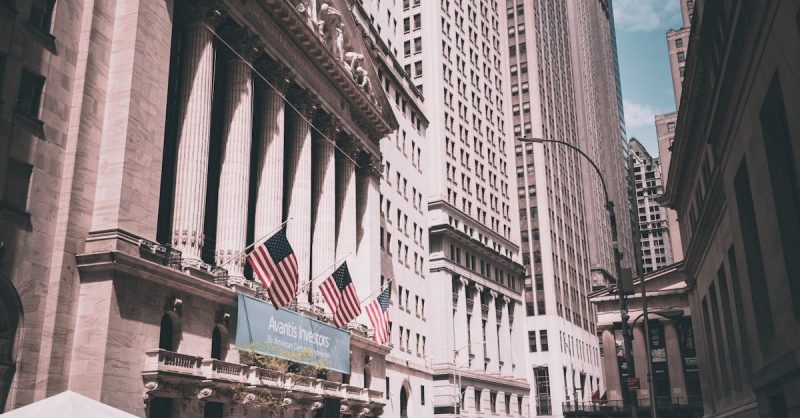 pexels-photo-16566782-16566782 View of New York Stock Exchange on a busy day with American flags and skyscrapers.
